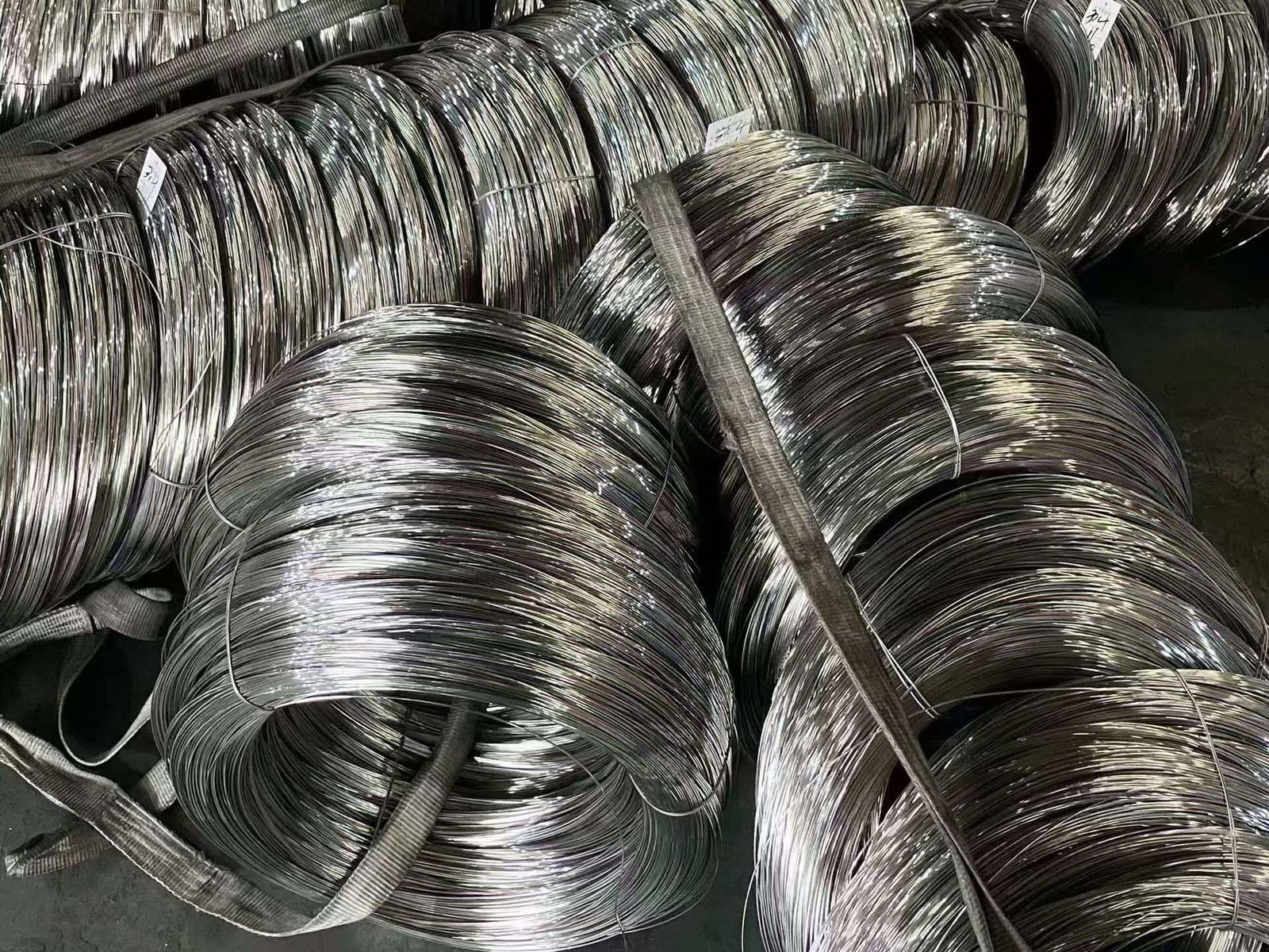 A calculator showing cost savings next to coils of 201 and 304 stainless steel wire